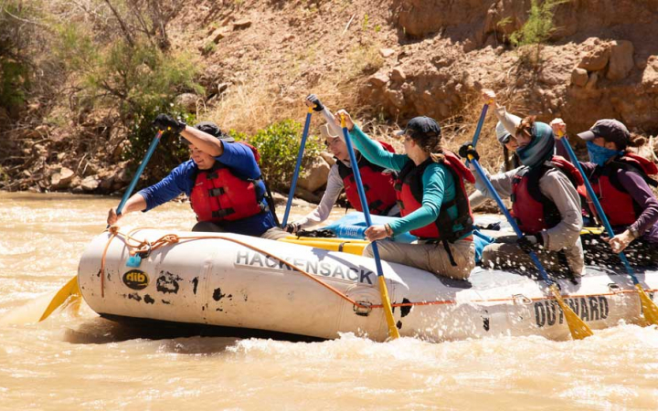 a group of veterans paddle a raft on an outward bound course